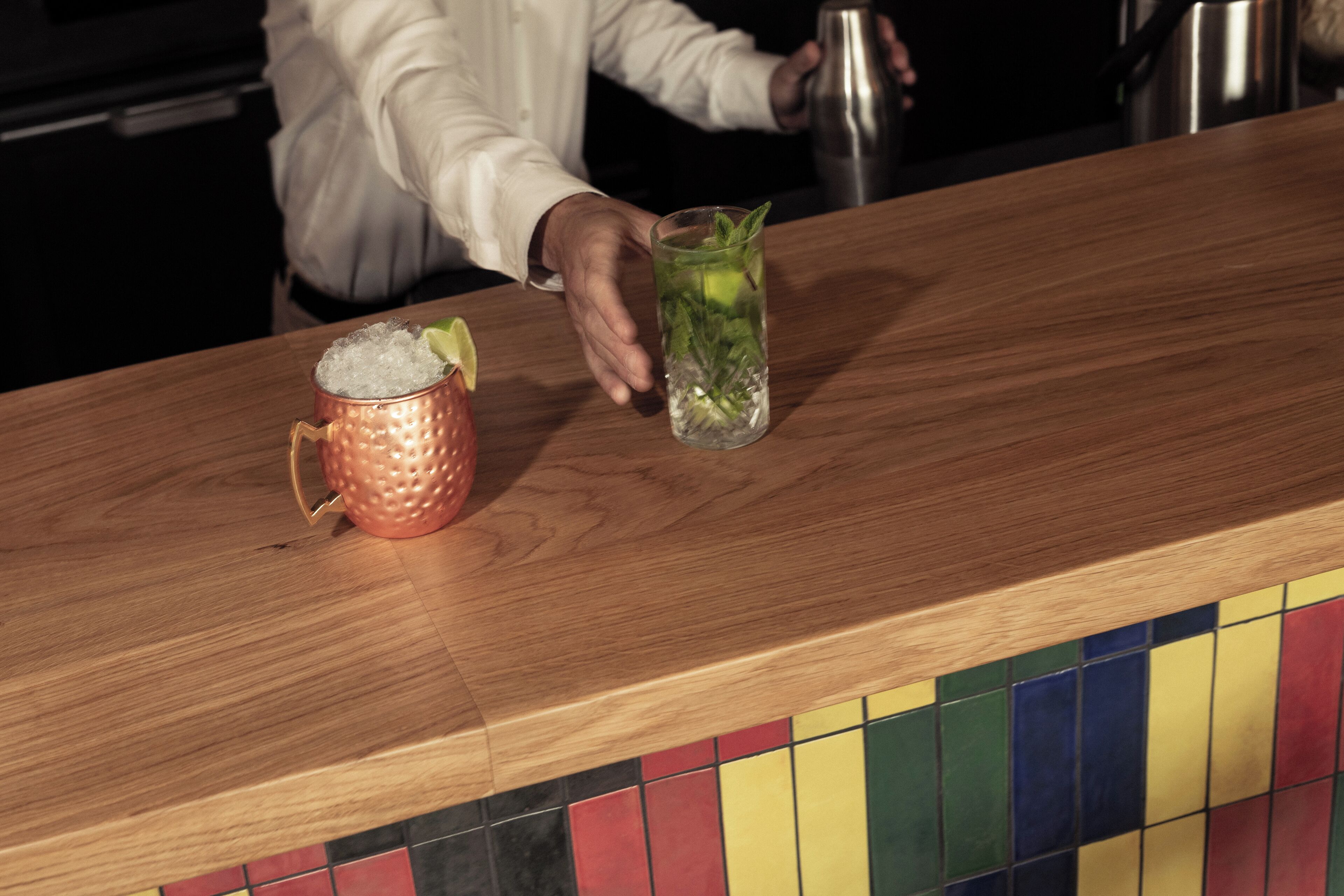 A bar area with a copper mug and a glass containing a drink garnished with mint.