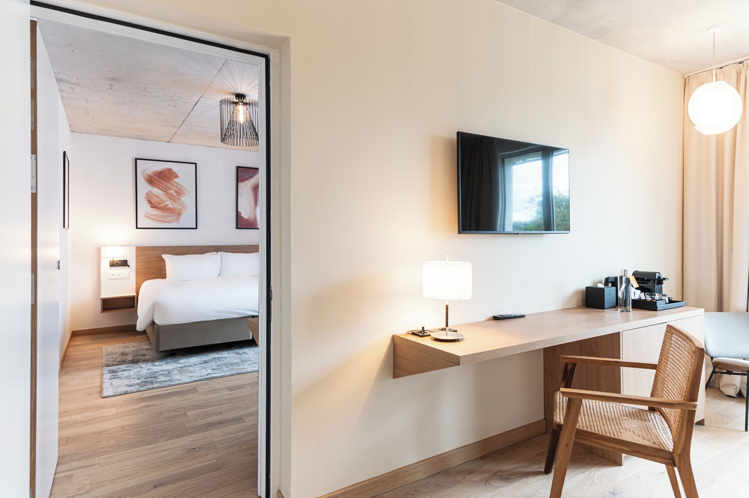 Une chambre d’hôtel moderne équipée d’un lit, d’un bureau, d’une chaise et d’un téléviseur.