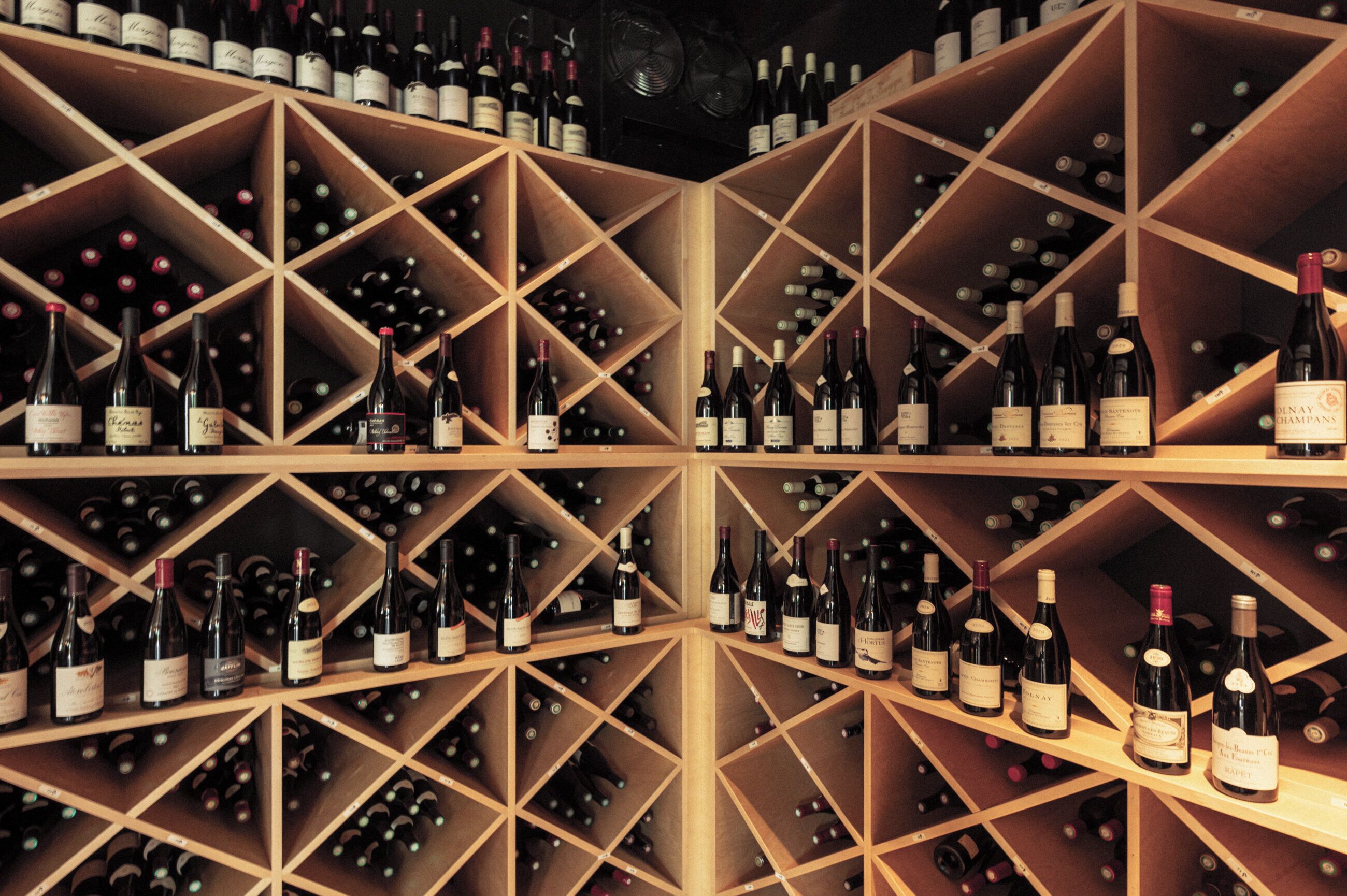 A wine cellar with wooden racks holding numerous wine bottles.