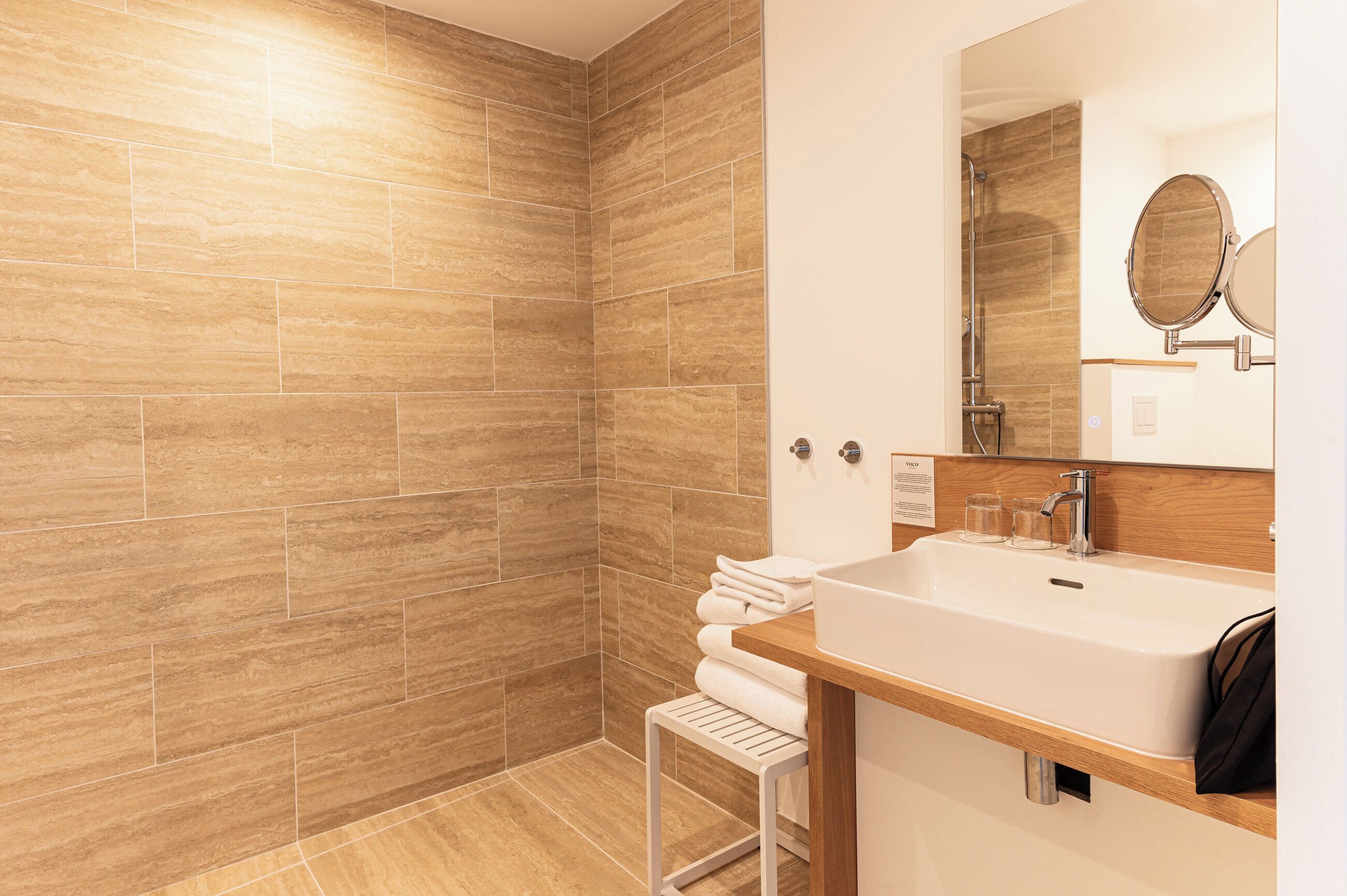 Un baño moderno con ducha, lavabo y espejo.