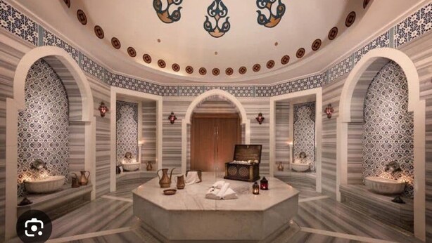 A luxurious spa room with a central seating area, patterned walls, and a decorative ceiling. - DAR SANAE SURF (Aourir)