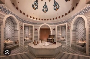 A luxurious spa room with a central seating area, patterned walls, and a decorative ceiling. - DAR SANAE SURF (Aourir)