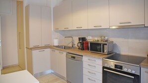 A modern kitchen with white cabinets, a dishwasher, a stove, and a microwave. - Athens Faliro Beach Residence, by the city center (Paleo Faliro)