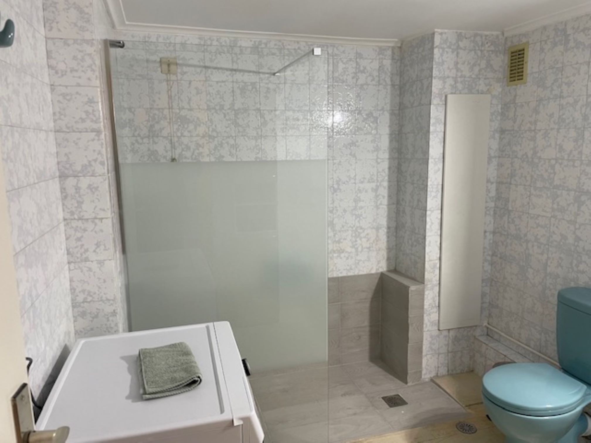 Et badeværelse med en brusekabine i glas, et toilet og en vask med et håndklæde.