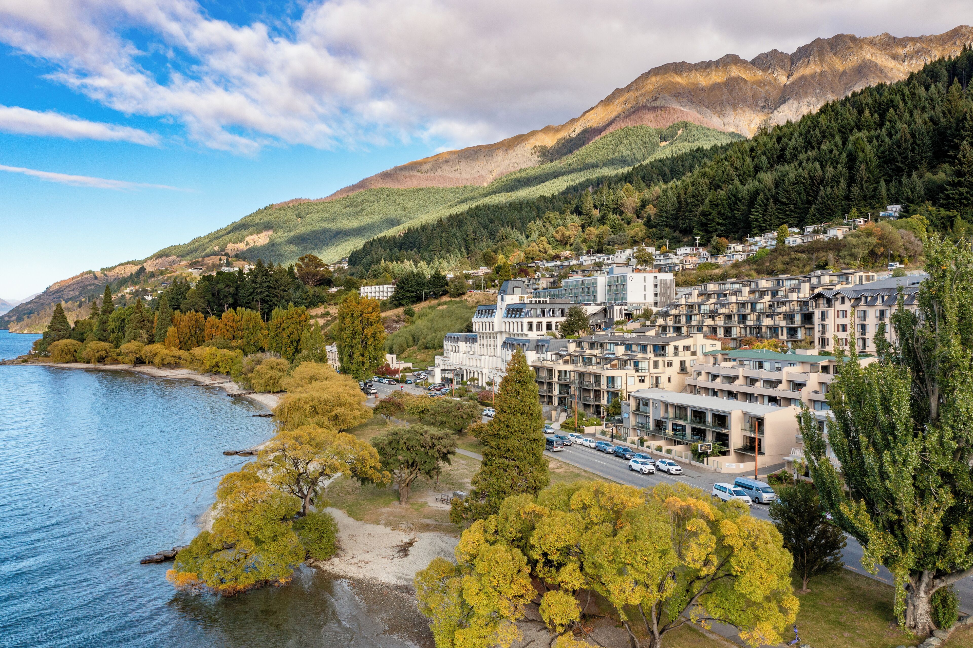A coastal town with a mix of residential and commercial buildings, a waterfront, and a mountainous backdrop.