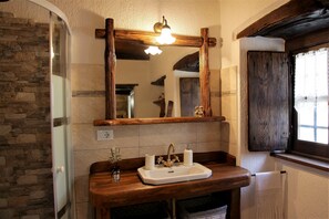 Un baño con pared de piedra, tocador de madera y un espejo.