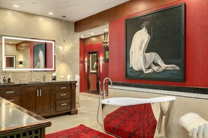 A modern bathroom with a large mirror, a bathtub, and a red textured wall. - Villa Fleuve (Ketchum)