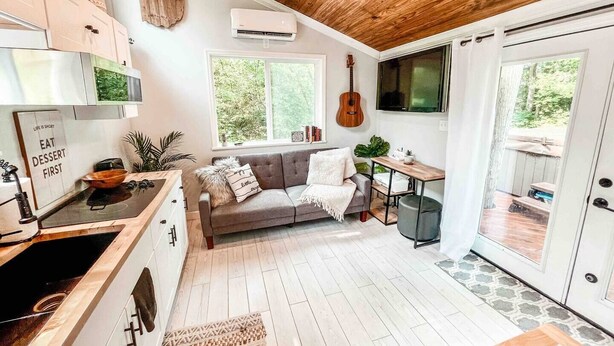 Una cucina moderna con piano cottura integrato, un divano grigio e un tavolo da pranzo.