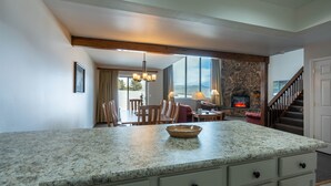 A kitchen with granite countertops, a stone fireplace, and a dining area with wooden furniture.