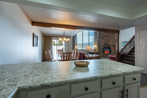 A kitchen with granite countertops, a stone fireplace, and a dining area with wooden furniture.