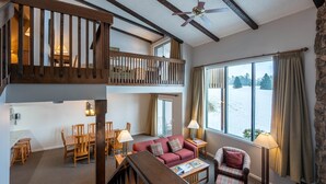 A spacious living area with a balcony, a dining set, and a cozy seating area.