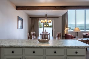 A modern kitchen with a granite countertop, a chandelier, and a dining area with a view.