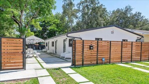 A modern house with a fenced yard, a driveway, and a small patio area. - Relax and Unwind Poolside Escape (Miami)