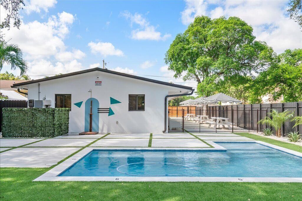 Une maison avec une piscine, un jardin clos et un arbre.