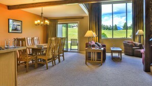 A spacious room with a dining area, a sofa, and a view of a grassy landscape through large windows. - Colden Lodge u15 - Enjoy Mountain Views (Lake Placid)