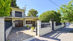 A two-story house with a gated entrance, a satellite dish, and a paved driveway.