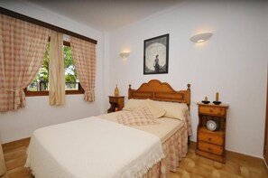 Une chambre à coucher avec un lit, des rideaux, une horloge murale et un tableau encadré.