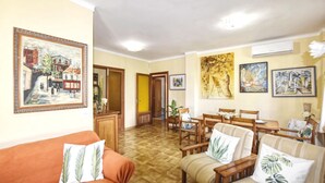 A living room with a sofa, chairs, a dining table, and artwork on the walls.