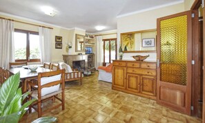 A spacious living area with a dining table, chairs, a sofa, and a fireplace. - Holiday Home 'Cora' with Private Terrace, Wi-Fi and Air Conditioning (Alcudia)