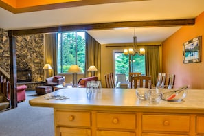 A kitchen with a large island, dining area, stone wall, and a fireplace.