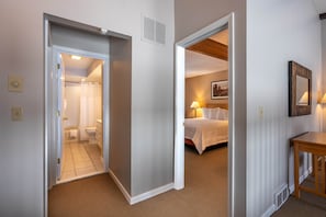 A hotel room with a bathroom, a bed, a bedside table, and a nightstand.