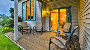 A covered porch with wooden flooring, two chairs, and a table.
