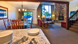A hotel room with a dining area, living room, and a stone fireplace.