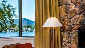 Ein Zimmer mit Blick auf ein Gewässer und Berge, ein Karomuster-Sofa, eine Lampe und eine Steinwand.
