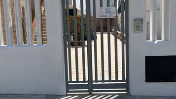 A gated entrance with a sign, a satellite dish, and a building facade.