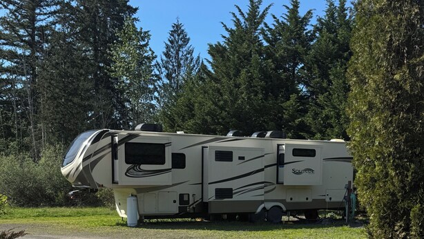 A recreational vehicle parked on a gravel path with a forested background. - RV SPACE:Tired of crowded, noisy RV parks? 5 private country acres with hookups. (Seabeck)