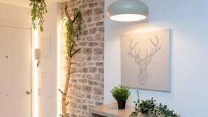 A modern interior with a stone wall, a wooden console table with plants, and a geometric deer head artwork. - Steps from Grandvalira  Cozy Ski Haven+Parking

 (Soldeu)