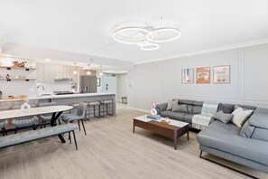 Uma sala de estar moderna com um sofá cinzento, uma mesa de centro e uma área de jantar com mesa e cadeiras.
