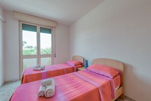Une chambre d’hôtel avec deux lits, une fenêtre et une vue sur la verdure.