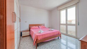 A bedroom with a bed, wooden wardrobe, and a large window. - Apartment 'Paola' with Private Terrace and Air Conditioning (san pietro in bevagna)