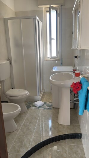 Une salle de bain équipée d’une douche, de toilettes, d’un bidet et d’un lavabo.