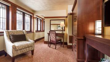 A room with a patterned armchair, a desk, and a large wooden cabinet.