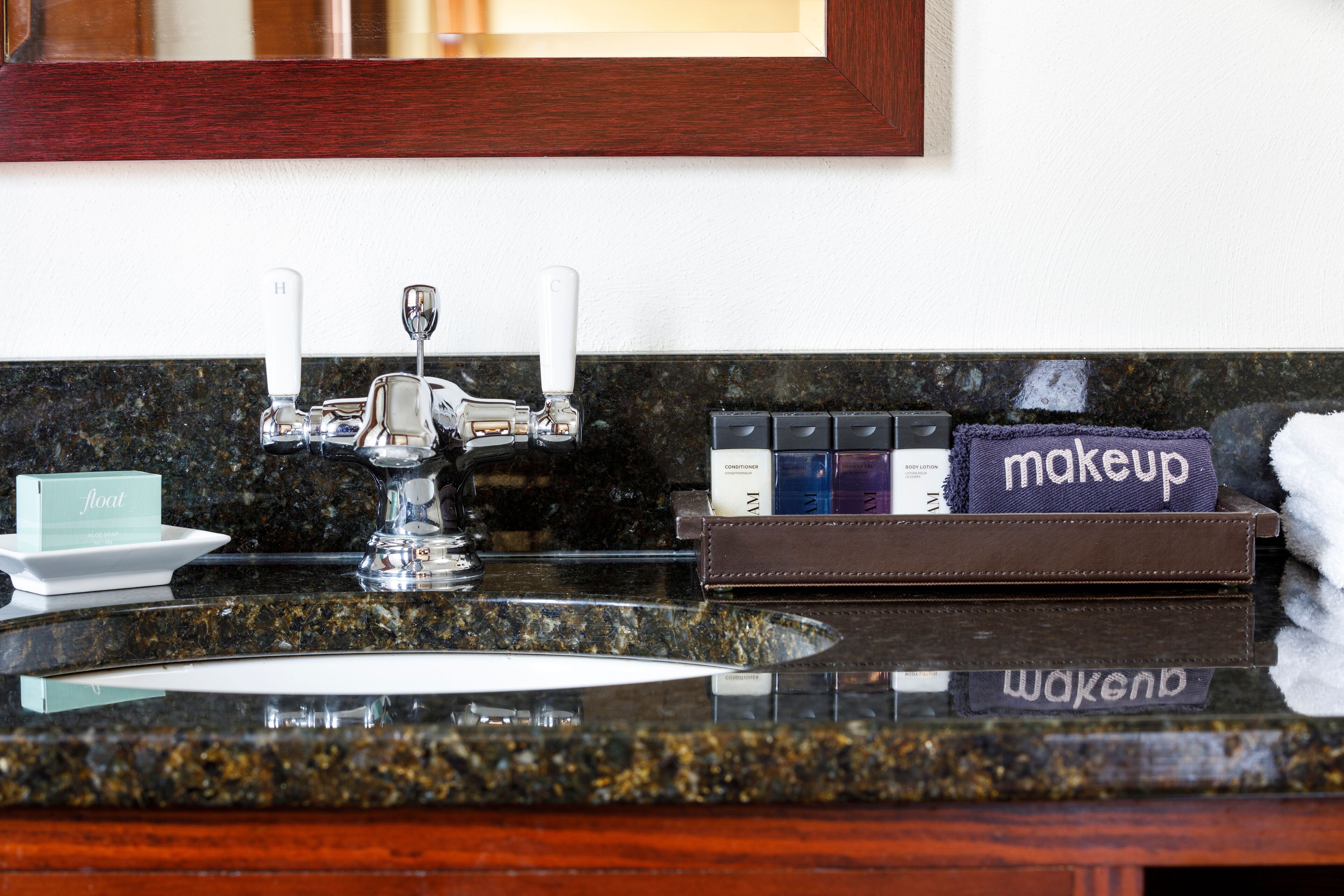 A bathroom vanity with a granite countertop, a silver faucet, and a makeup organizer containing various items.