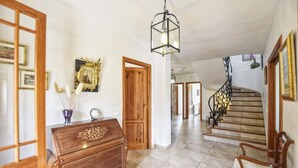 A spacious hallway with a wooden staircase, a vintage-style chandelier, and a wooden dresser. - Holiday Home 'Pla De Ses Rotes' with Mountain View, Wi-Fi and Air Conditioning (Campanet)