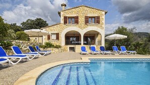 A stone building with a swimming pool, blue lounge chairs, and umbrellas. - Holiday Home 'Pla De Ses Rotes' with Mountain View, Wi-Fi and Air Conditioning (Campanet)
