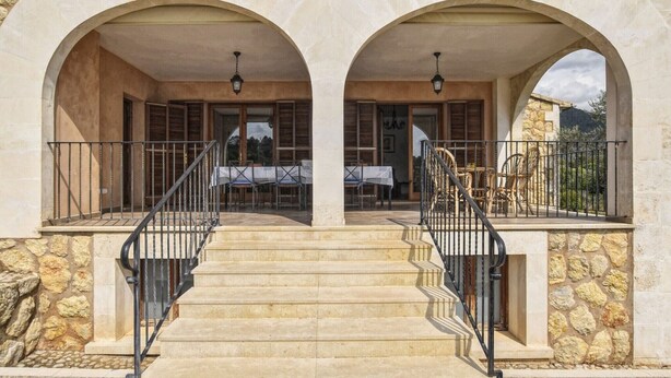 A stone building with a central staircase, two arches, and a balcony with outdoor furniture. - Holiday Home 'Pla De Ses Rotes' with Mountain View, Wi-Fi and Air Conditioning (Campanet)