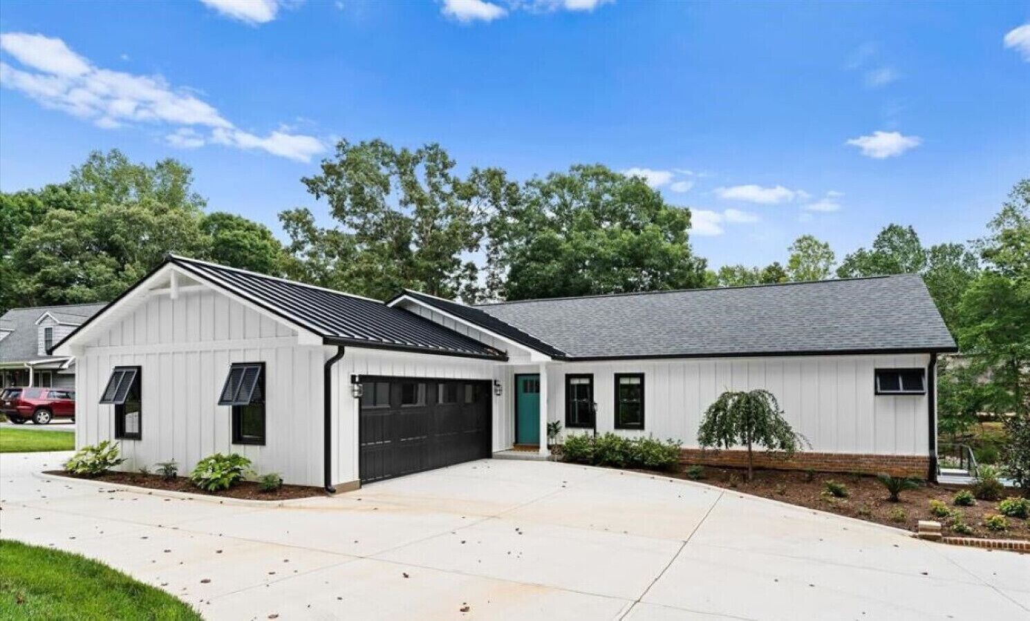 Une maison de plain-pied avec un garage, une véranda et un petit jardin.