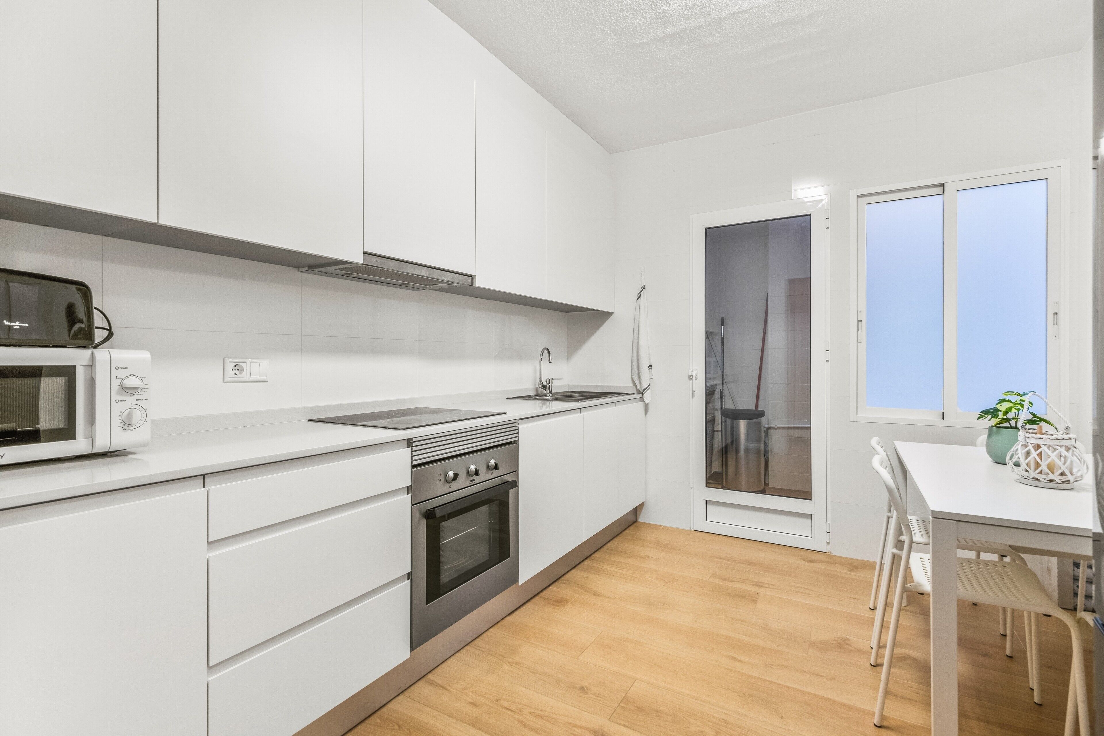 Een moderne keuken met witte kasten, een roestvrijstalen oven en een magnetron.