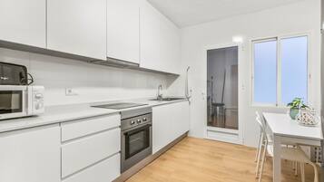 Een moderne keuken met witte kasten, een roestvrijstalen oven en een magnetron.