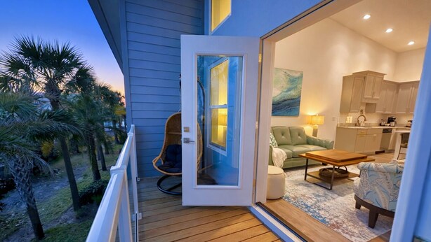Een modern huis met een balkon, een rieten stoel, een bank, een eettafel en een keuken.