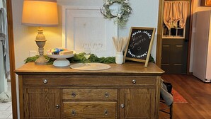 A wooden dresser with drawers, a lamp, a cake on a stand, a glass, and a chalkboard with a message. - Enjoy rural Missouri and a quiet getaway at White Cottage Farm. (Bogard)