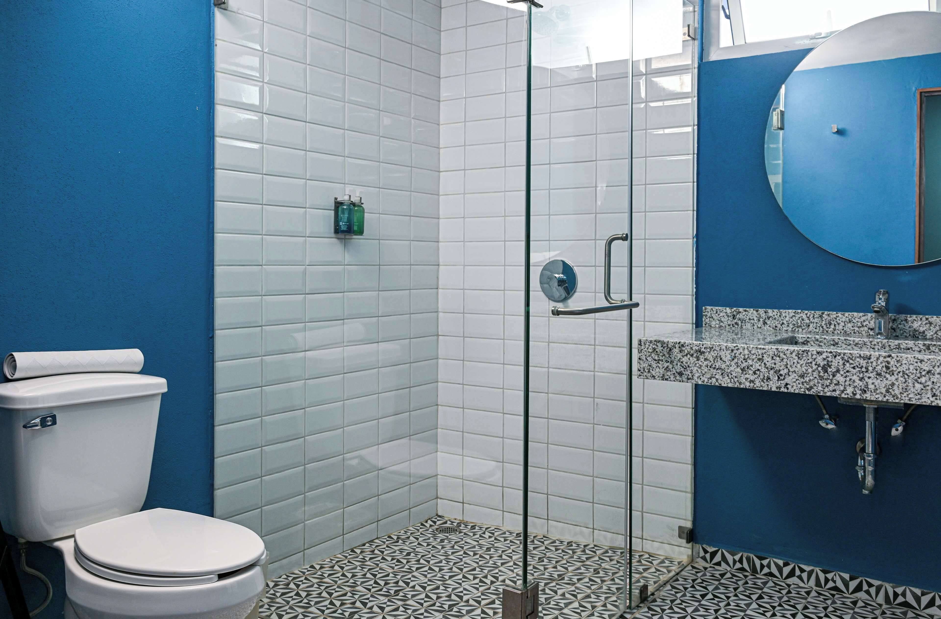 A bathroom with a white toilet, a glass shower enclosure, and a sink with a granite countertop.