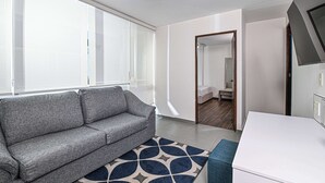 A modern living room with a grey sofa, a patterned rug, and a white table.