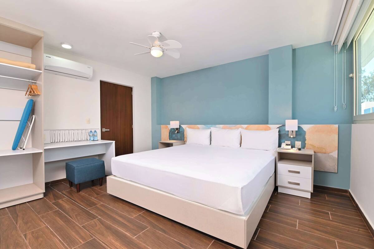 Een moderne slaapkamer met een groot bed, een bureau en een plafondventilator.