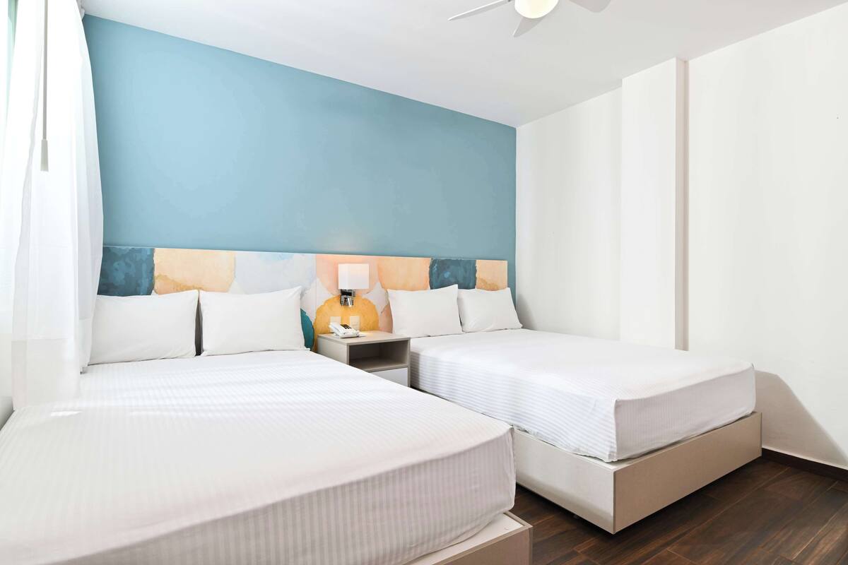 Een hotelkamer met twee bedden, een nachtkastje en een plafondventilator.