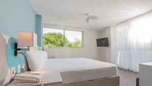 A modern hotel room with a bed, bedside table, lamp, phone, and a TV on the wall.